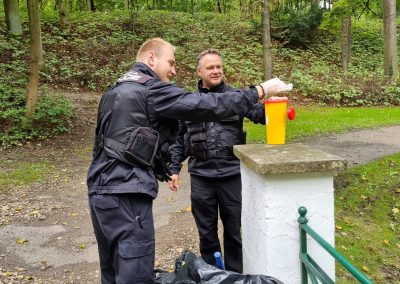 Dva strážníci MP Žatec ukládají nalezenou injekční stříkačku do žluté nádoby.